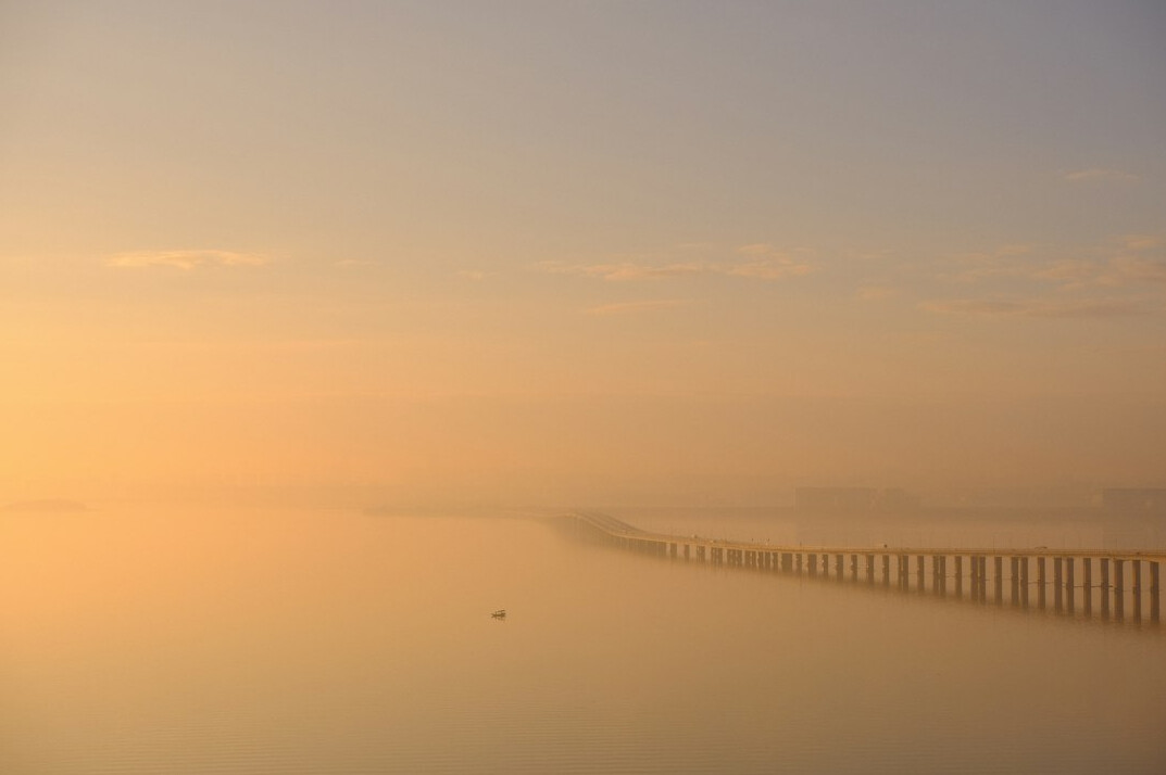 Misty bridge at dawn over calm water